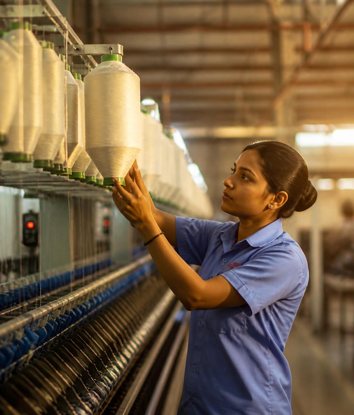 Technician inspecting yarn cones inside a textile manufacturing plant